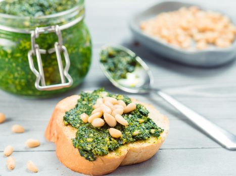 Close up view of baguette bread with fresh basil pesto sauce on gray wooden table. Copy space.