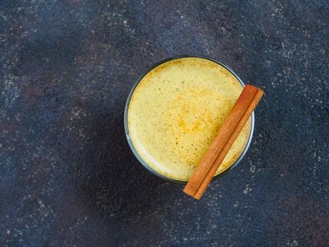 Healthy drink golden turmeric latte in glass.Gold milk with turmericy on black cement background. Detox turmeric tea with copy space. Top view or flat-lay