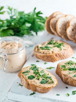 Close up view of slice bread with homemade turkey pate and fresh green parsley on white rustic kutting board over white concrete background, Shallow DOF. Selective focus