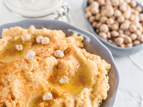 Homemade hummus with olive oil in gray bowl and tahini. Traditional middle eastern homemade appetizer hummus - healthy vegan paste snack. Vegetarian diet and nutrition protein food concept and idea