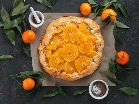 Top view of caraway and orange tart on baking paper over black cement background. Winter season and christmas ideas recipe - tart with caraway pastry and oranges, mandarines or tangerines.