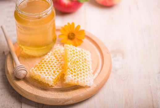 Honey dipper on the bee honeycomb background. Honey tidbit in glass jar and honeycombs.