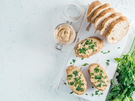 Top view of slice bread with homemade turkey pate and fresh green parsley on white rustic kutting board over white concrete background, Shallow DOF. Selective focus Copy space.