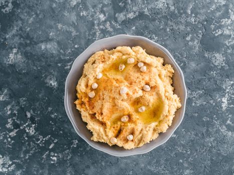 Homemade hummus in gray bowl and tahini. Traditional middle eastern homemade appetizer hummus - healthy vegan paste snack. Vegetarian diet,nutrition protein food concept and idea.Top view or flat-lay.