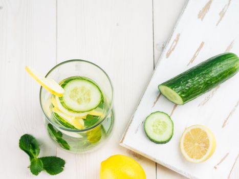 Infused detox water with cucumber, lemon and mint in glass bottle on white table. Diet, healthy eating, weight loss concept. Copy space. Top view or flat-lay.