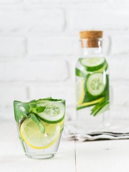 Infused detox water with cucumber, lemon and mint in glass and bottle on white table. Diet, healthy eating, weight loss concept. Copy space