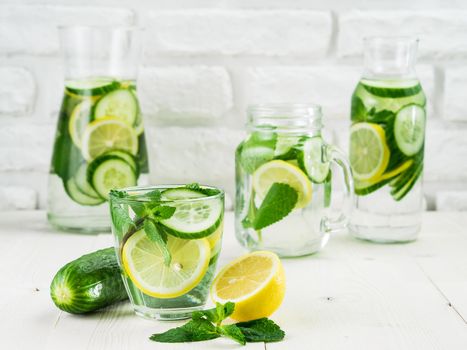 Infused detox water with cucumber, lemon and mint in different glass bottles on white table. Diet, healthy eating, weight loss concept. Copy space