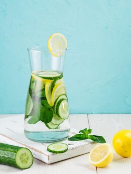 Infused detox water with cucumber, lemon and mint in glass bottle on white table. Diet, healthy eating, weight loss concept. Copy space