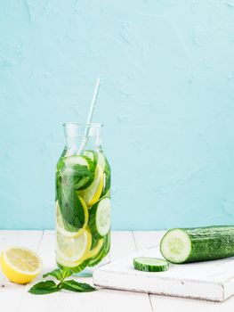 Infused detox water with cucumber, lemon and mint in glass bottle on white table. Diet, healthy eating, weight loss concept. Copy space