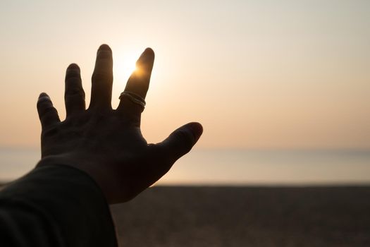 Hand reach out to sunset sky beach sand nature background. Relax and rest in vacation time.