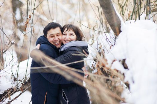 Winter portrait of a young interracial couple as they hug each other.