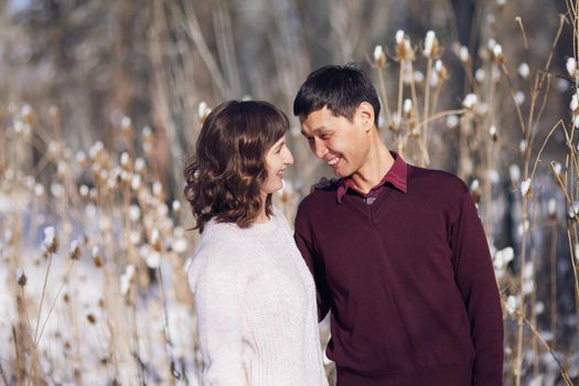 Warm winter portrait of young interracial smiling couple on a walk in the forest.