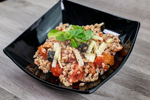 served on black plate of farroset salad on wooden table