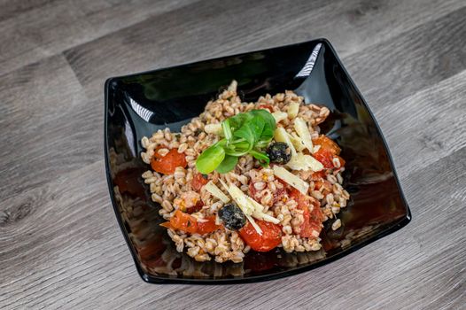 served on black plate of farroset salad on wooden table