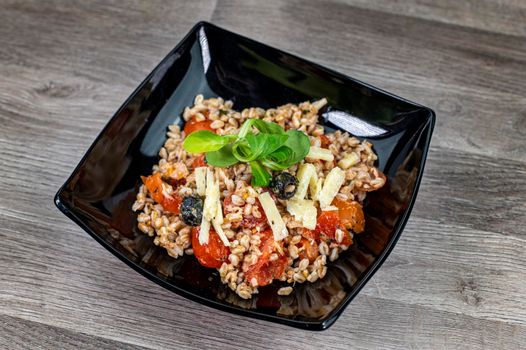served on black plate of farroset salad on wooden table
