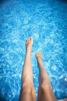 Slim legs of young woman in swimming pool. Summer time