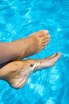 Slim legs of young woman in swimming pool. Summer time