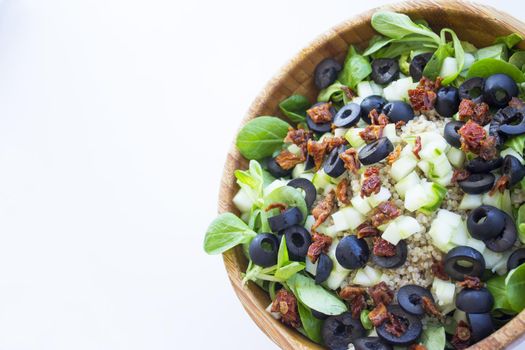 Quinoa, lettuce, lambs lettuce, black olives and cucumber salad. No people