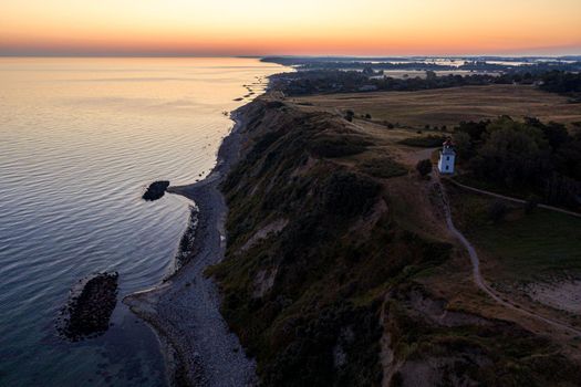 Hundested, Denmark - August 15, 2020: Aerial drone view of Spodsbjerg lighthouse and the coastline during sunrise