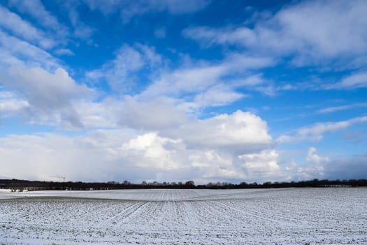 Beautiful clouds in the sky looking over a snow covered agricultural field
