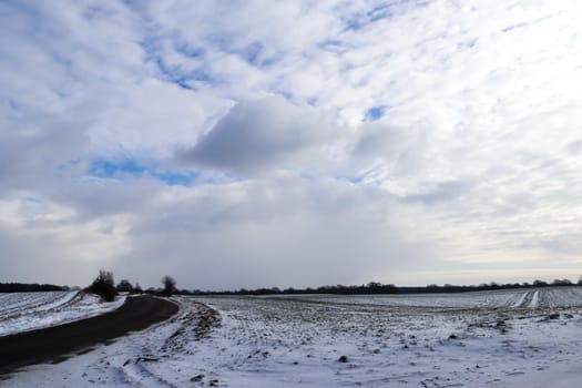 Beautiful clouds in the sky looking over a snow covered agricultural field