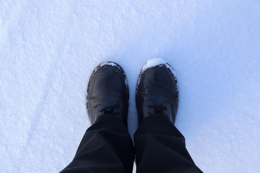 High angle view at black boots standing in fresh snow