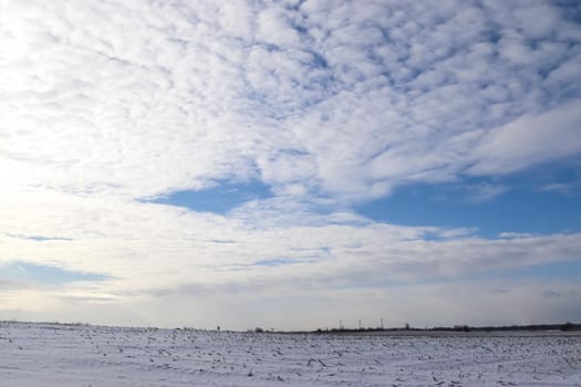 Beautiful clouds in the sky looking over a snow covered agricultural field