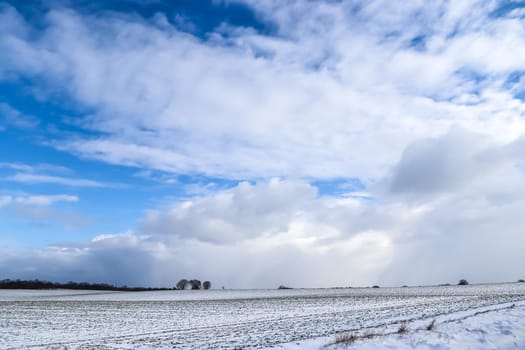 Beautiful clouds in the sky looking over a snow covered agricultural field