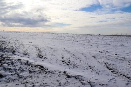 Beautiful clouds in the sky looking over a snow covered agricultural field