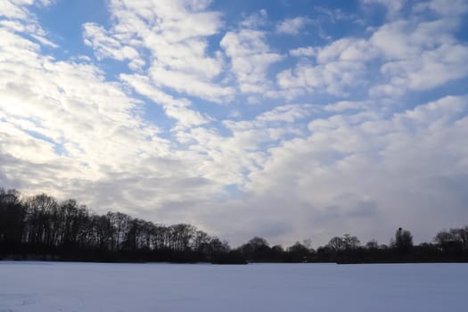 Beautiful clouds in the sky looking over a snow covered agricultural field
