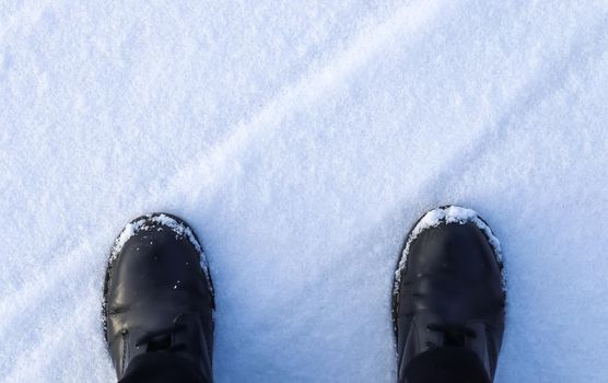 High angle view at black boots standing in fresh snow
