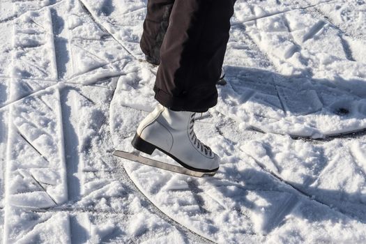 Close up on womans feet wearing ice skating boots and standing on ice