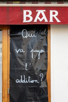 ESPELETTE, FRANCE - 21 FEBRUARY, 2021: Banner at Pottoka restaurant reads who is going to pay the bill. Restaurants and bars in France are closed since 29 October, 2020 to curb the Covid-19 pandemic.