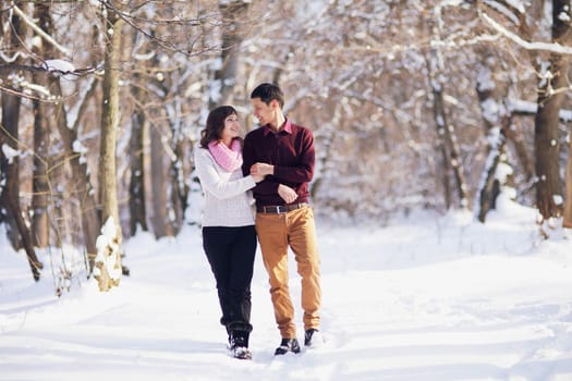 Young couple walking through the winter forest holding hands.