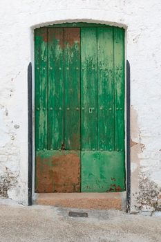 old green painted wooden door in a stone wall in southern in spain