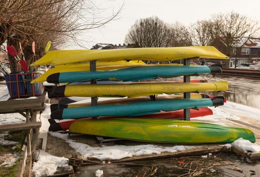 canoes and paddles lie on the shore in winter during the frost period in the netherlands