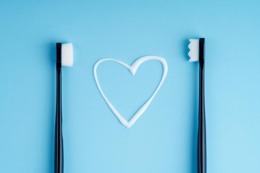 Heart shaped toothpaste between two toothbrushes.