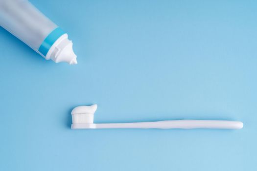 Fashionable toothbrush with soft bristles. Popular toothbrushes. Hygiene trends. Top view with a tube of toothpaste applying on brush.