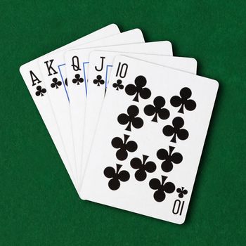 A hand of cards clubs royal flush on green card table cloth winning hand business concept
