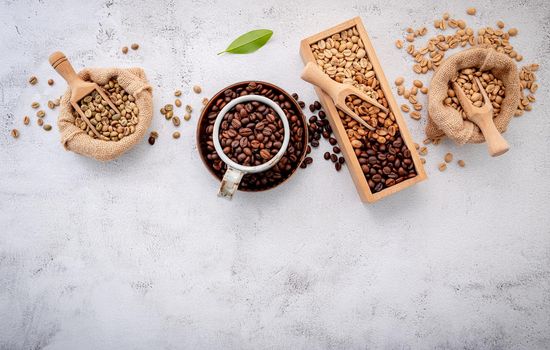 Roasted coffee beans with scoops setup on white concrete background.