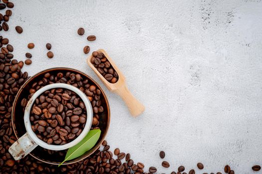 Roasted coffee beans with scoops setup on white concrete background.