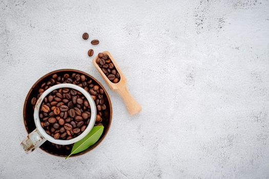 Roasted coffee beans with scoops setup on white concrete background.