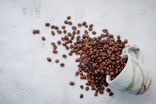 Roasted coffee beans with scoops setup on white concrete background.