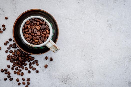 Roasted coffee beans with scoops setup on white concrete background.