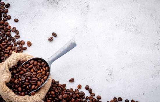 Roasted coffee beans with scoops setup on white concrete background.