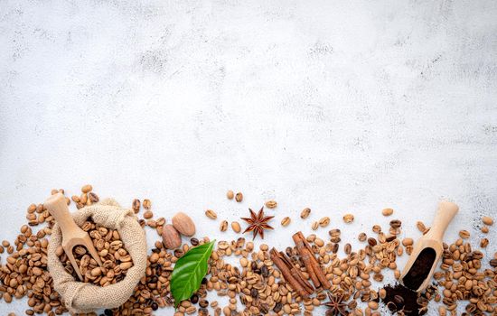 Roasted coffee beans with scoops setup on white concrete background.