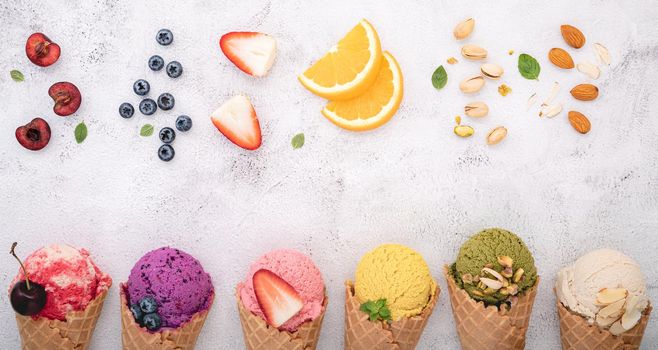 Various of ice cream flavor in cones blueberry ,pistachio ,almond ,orange and cherry setup on white stone background . Summer and Sweet menu concept.