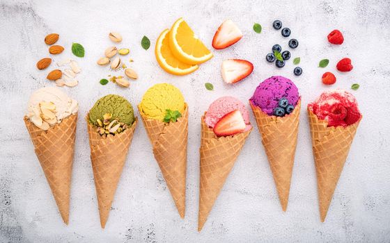 Various of ice cream flavor in cones blueberry ,pistachio ,almond ,orange and cherry setup on white stone background . Summer and Sweet menu concept.