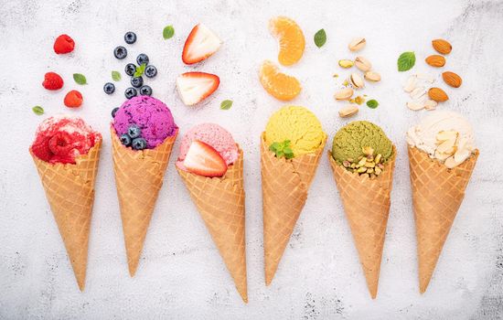 Various of ice cream flavor in cones blueberry ,pistachio ,almond ,orange and cherry setup on white stone background . Summer and Sweet menu concept.