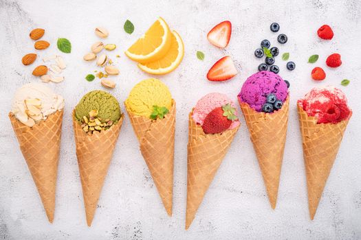 Various of ice cream flavor in cones blueberry ,pistachio ,almond ,orange and cherry setup on white stone background . Summer and Sweet menu concept.